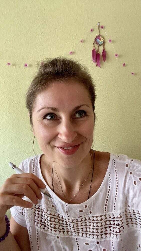 Noreen beim inspirierten Nachdenken mit einem lächenlden Gesicht und einem Sift in der Hand